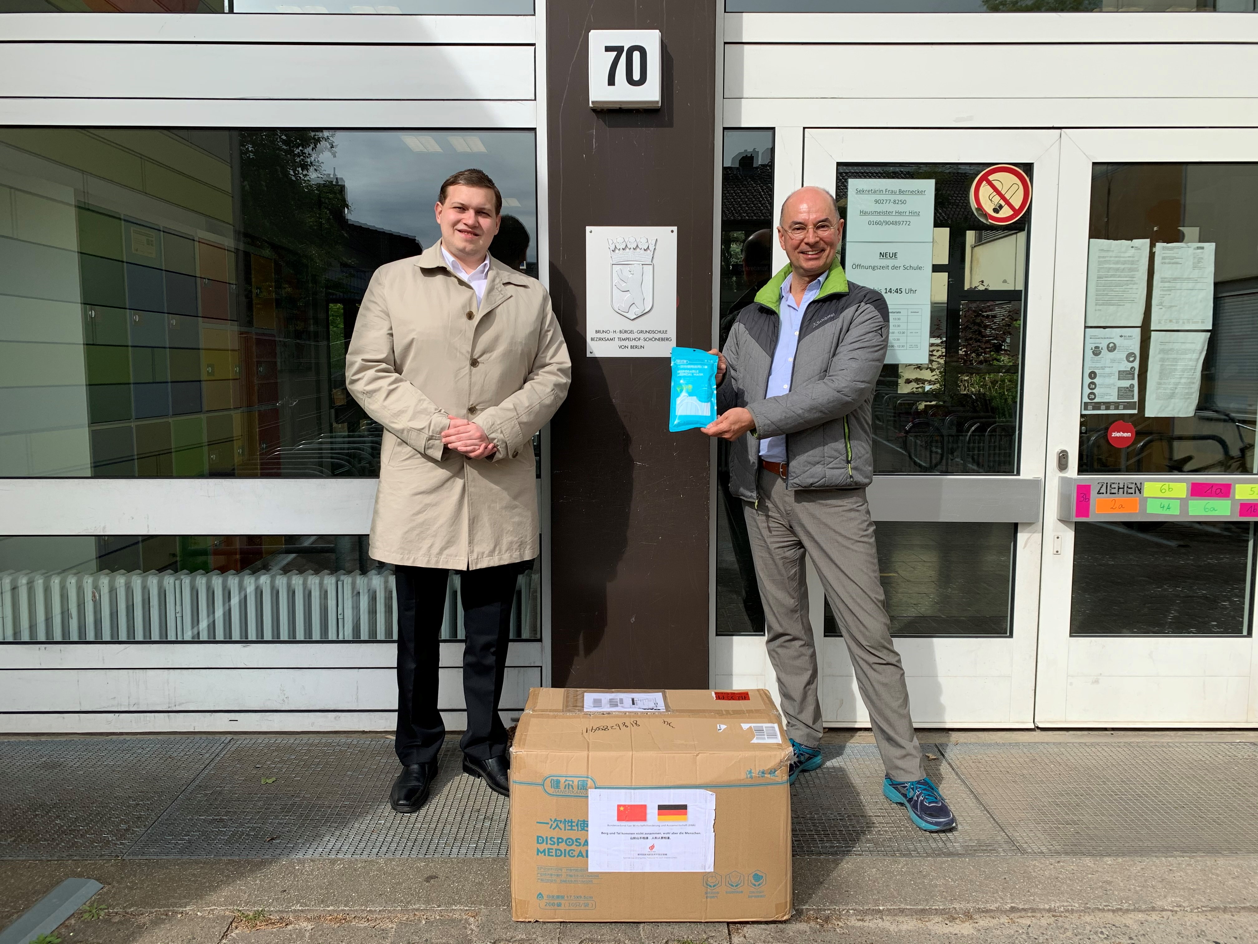 BWA-Geschäftsträger Urs Unkauf übergibt die Maskenspende aus China an Jens Otte, Schulleiter der Bruno-H.-Bürgel-Grundschule in Berlin-Lichtenrade.